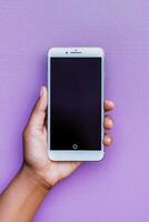 Hand holding a smartphone against a vibrant purple background in a modern setting photo