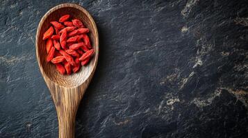 Goji berries served in a wooden spoon on a dark stone surface for healthy eating and nutrition photo