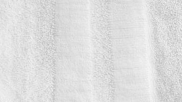 Soft and fluffy white towel hanging against a neutral background in a bright bathroom setting during daylight hours photo