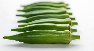 Fresh Okra Pods in a Row on White Surface Ready for Cooking photo
