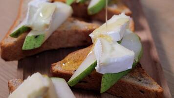 Slices of pear and soft cheese on toasted bread with honey drizzle, capturing a fresh gourmet appetizer made from natural ingredients and simple homemade elements video
