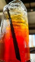 Condensation on a glass of iced tea. Blurred red and yellow bokeh with water droplets, photo