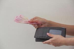 Hand taking rupiah money from brown wallet, white background. photo