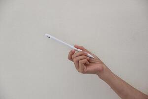 Technology Concept. One Hand using Tablet in Vertical axis with white stylus or pen and free screen on white background and clipping path. photo