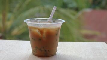 A cup of traditional indonesian iced drink green cendol with brown sugar and coconut milk with a spoon on a wooden table. photo