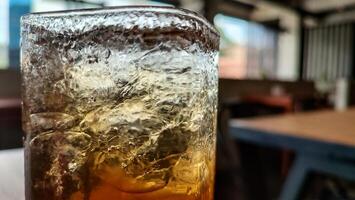 Condensation on a glass of iced tea. Blurred red and yellow bokeh with water droplets photo