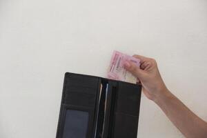 Hand taking rupiah money from brown wallet, transaction process or buying and selling. white background. photo