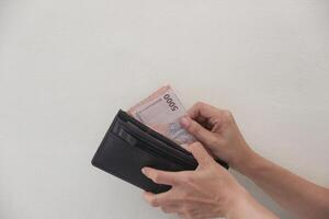 Hand taking rupiah money from brown wallet isolated on white background photo