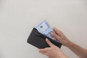 Hand taking rupiah money from brown wallet isolated on white background. photo
