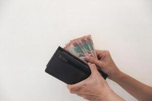 Hand taking rupiah money from brown wallet, transaction process or buying and selling. white background photo