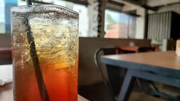 Condensation on a glass of iced tea. Blurred red and yellow bokeh with water droplets. photo