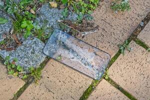 An old broken Display-Glass Smartphone in Soapy Water on Paved Surface photo