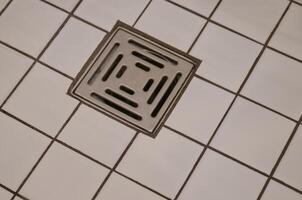 Close-up of Square Metal Drain Cover on Tiled Floor photo