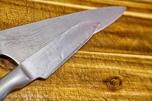 Close-up of a sharp kitchen knife resting on a wooden cutting board, showcasing the blade's edge and texture. photo