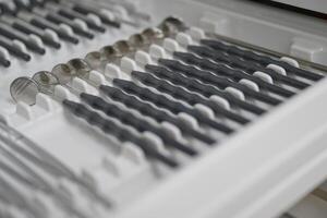 A close-up view of dental instruments neatly arranged in a tray. The instruments include various types of mirrors and explorers, showcasing their shiny metallic surfaces and precise designs. photo
