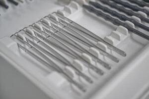 A close-up view of a set of surgical instruments neatly arranged in a tray. The instruments include various types of tweezers and scalpels. photo