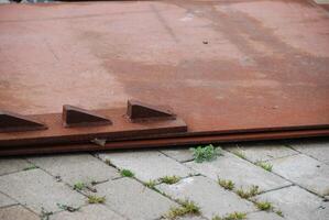 Rusted Metal Sheets on Stone Pavement photo