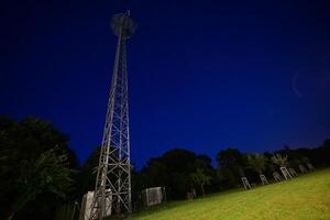 Night View of a Communication Tower in a Grassy Field photo