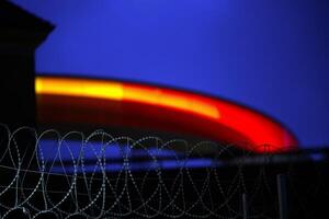 Colorful Circular Structure Behind Barbed Wire at Twilight photo