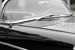A black and white photo of a car with rain drops on it