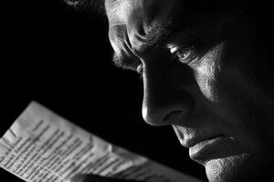 A man reading a newspaper while looking down photo