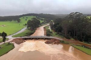 A river is flowing through a field with a bridge photo