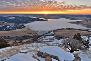 A view of the sun setting over a lake and mountains photo