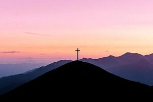 A cross on top of a mountain at sunset photo
