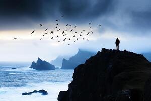 A person standing on a cliff overlooking the ocean photo