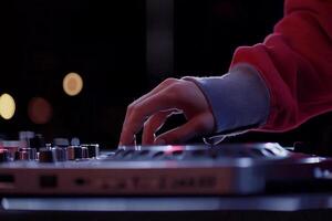 A person is playing a dj mixer with lights on photo