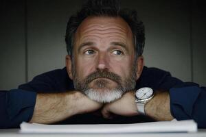 A man with a watch and a beard is looking at the camera photo