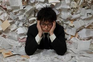 A man in a suit and tie sitting on top of a pile of papers photo