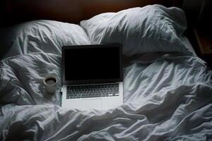 A laptop and coffee cup on a bed photo