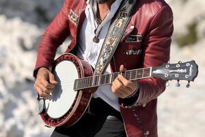 A man in a red jacket playing a banjo photo