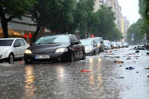 A car is driving through a flooded street photo