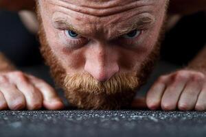 A man with a beard and a red beard is doing push ups photo