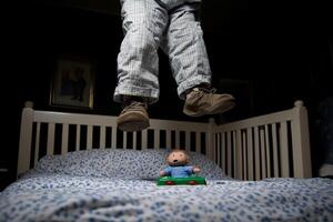 A person jumping in the air with a toy on a bed photo