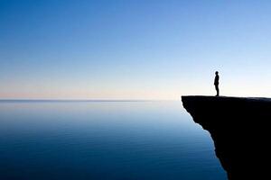 A man standing on the edge of a cliff overlooking the ocean photo