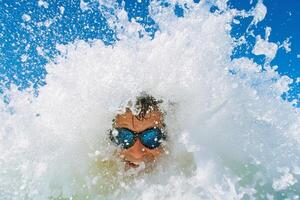 A man in sunglasses is splashing water in the ocean photo