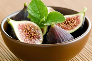 A bowl of figs with a leaf on top photo