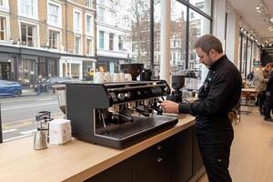 A man is standing in front of a coffee machine photo