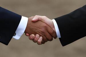Two men shaking hands in front of a gray background photo