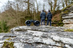Two people looking at a pair of binoculars on a rock photo