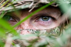 A man in camouflage is looking through the grass photo