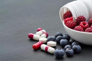 A white pill bottle with raspberries and blueberries photo