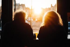 Two people sitting at a table looking out the window at the sun photo