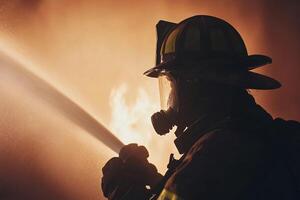 A firefighter with a hose in front of a fire photo