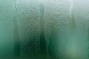 A wet window with water droplets on it photo