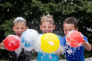 Three boys playing with foam balls in the rain photo