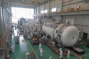 A large white machine in a factory with people working photo